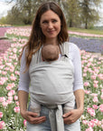 Frau trägt Baby in den Loops mit dem Übertuch "moon", Tulpenfeld im Hintergrund.