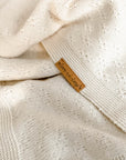 Detailaufnahme der Babydecke, naturfarben, mit braunem Lederlabel "love-in-loop"