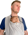Mann trägt Baby in den Loops und hat die Nackenrolle n Benutzung, diese befindet sich im Nacken des Babys und unter den Loops