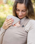 Nahaufnahme, Frau trägt Baby in Loops und Übertuch in "toffee", hält eine Hand am Köpfchen des Baby und schaut auf ihr Baby.
